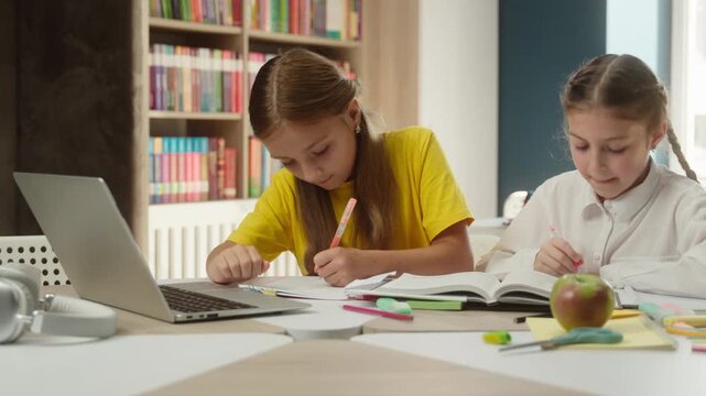 Focused Caucasian little girls children studying laptop indoors class elearning kids schoolgirls students classmates teenagers writing task schoolwork internet digital online lesson modern education