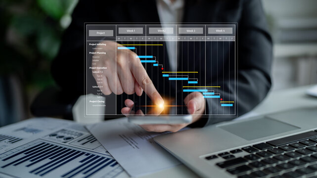 A business professional uses a smartphone to analyze a Gantt chart alongside a laptop, visualizing project timelines in a modern office for enhanced planning and organization. Tessel