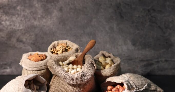 Different types of nuts in bags on black table, zooming