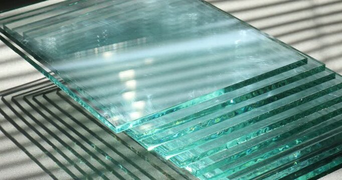Stack of glass sheets on grey table, closeup. Camera moving right