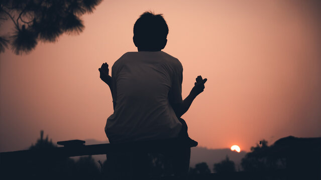 Human lift two hands up and praying to God on sky with light sunset background, christian silhouette concept.