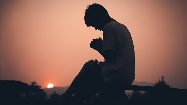 Human praying with light sunset background, christian silhouette concept.