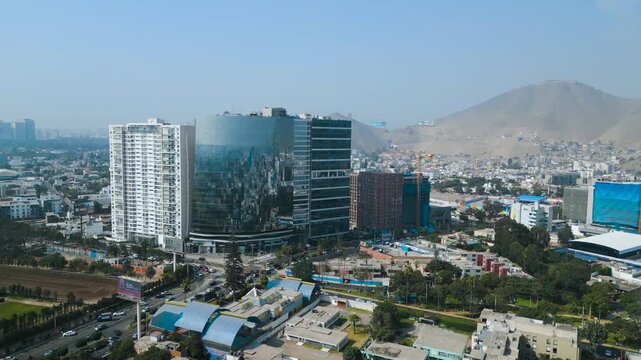 4K cinematic drone panorama of Lima Central Tower in Surco, showcasing the modern glass architecture of El Derby business district on a sunny autumn afternoon.