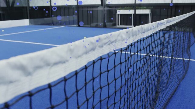 Tennis net occupying foreground, camera gliding low, blue particles drifting to reveal court depth