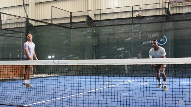 Two male players reacting to opponent contact, volleying paddles, chasing yellow ball on blue court