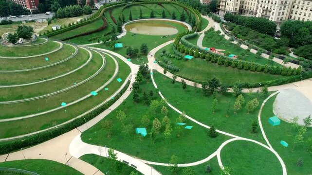 Camera pulling back, panning park showing terraces paths, pond, turquoise tarps revealing buildings