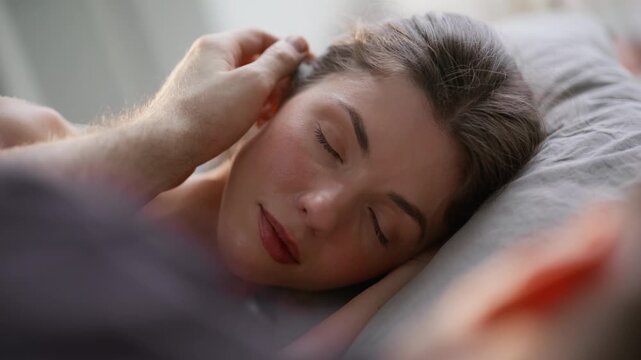Man fingers stroking woman hair at bed closeup. Intimate couple lying at morning