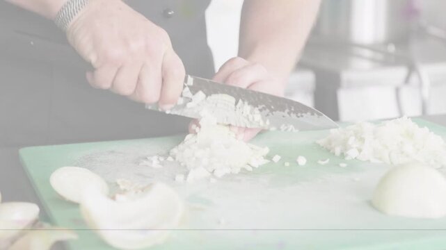 Cook's hands placing knife, rocking and chopping onion on green board, forming mince for cooking