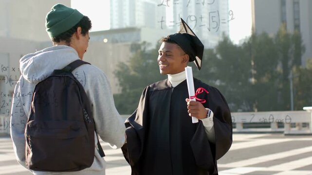 Peer approaching graduate shaking hands then shoulder pat for graduation as math graphs rising