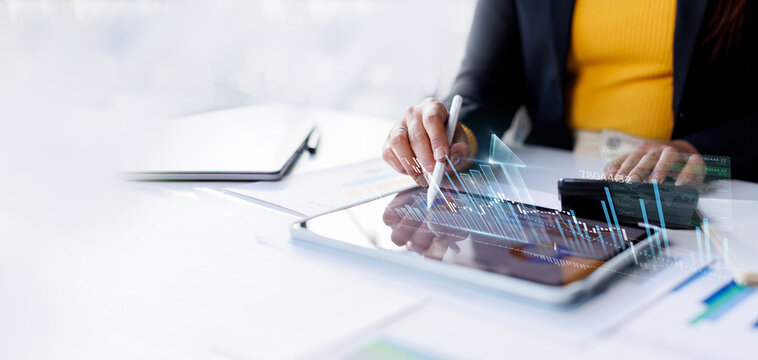 Businesswoman using stylus on digital tablet with virtual financial growth graph, stock market analysis and data visualization complex financial chart, data analytics, and numbers finance concept