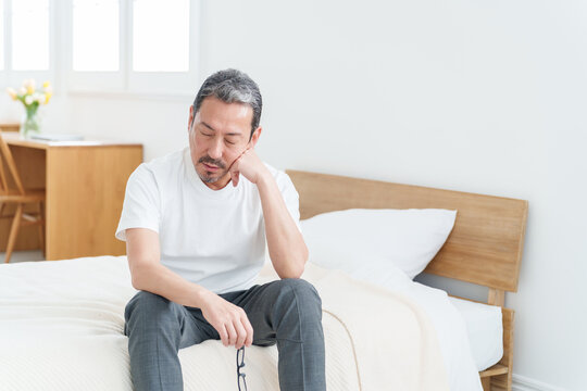 ベッドで休む疲れた表情の中高年男性