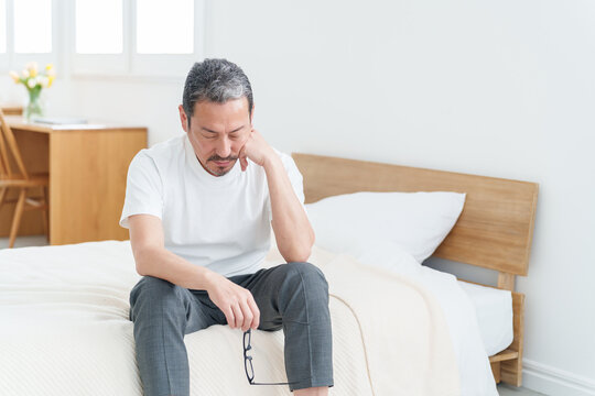 ベッドで休む疲れた表情の中高年男性