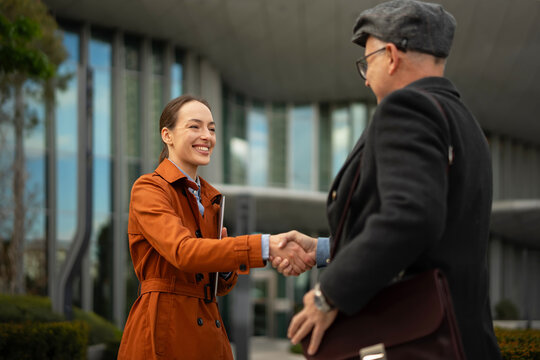 Businesswoman and businessman shaking hands in urban setting