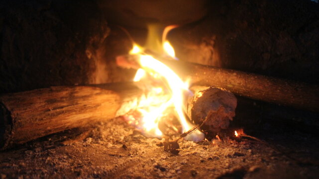 Close up of burning wood logs blazing in flames inside black wrought iron wood burning fire.