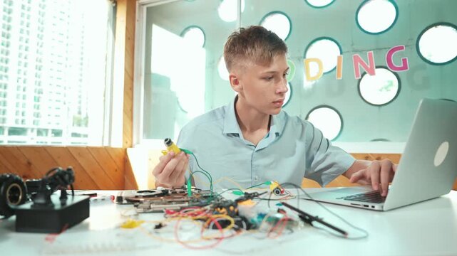 Smart happy boy inspect or learning to use electronic tool to fix car model. high school student studying about electric equipment to repair robotic machines while sitting at STEM class. Edification