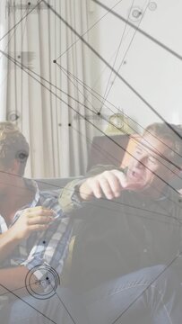 Vertical video: Dad raising arm grabbing wrist seizing football on couch with playful sports HUD
