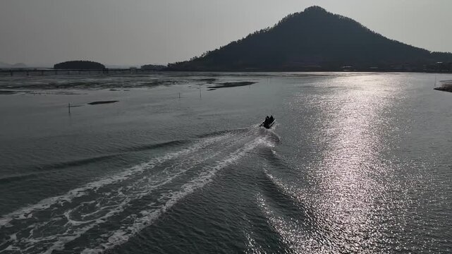 Fishing boat leaving a white wake on the sea for seaweed farming, Sinan