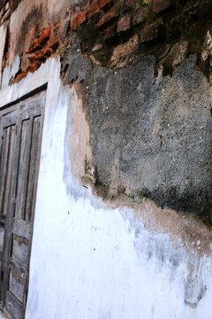 The old building walls with peeling paint and plaster that has crumbled due to high humidity