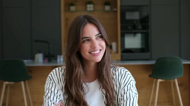 A beautiful young woman with a radiant smile looks around a modern home, exuding happiness and positive emotions. Her relaxed demeanor suggests contentment and well-being.