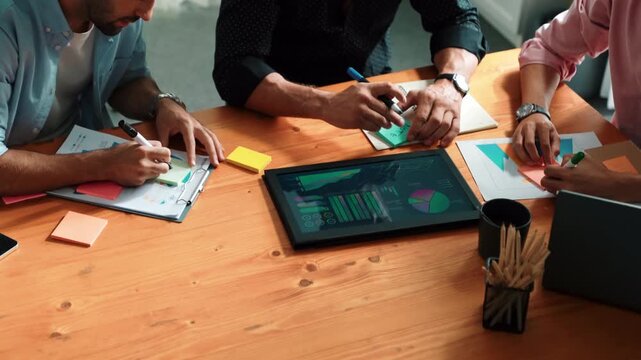 Closeup of business team hand brainstorm idea by using sticky notes at meeting table with tablet display financial graph. Group of diverse people planning about start up project strategy. Convocation.