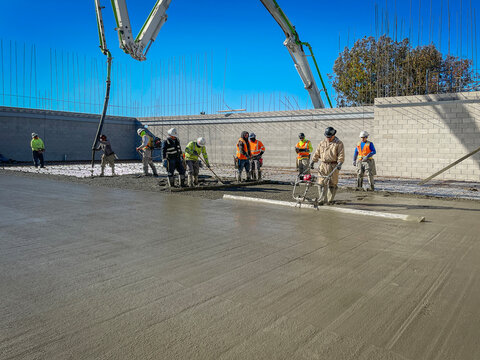 Construction workers pouring concrete slab at a commercial job site