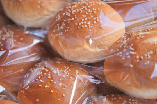Sesame seed buns stacked in clear plastic wrapping