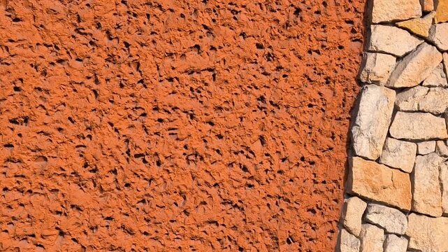 Orange plaster wall with natural stone border, terracotta texture background, rustic masonry detail, candid style video, architectural facade material, Mediterranean building surface.