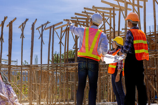 Structural engineer, architect and foreman worker with blueprints discuss, plan working for the outdoors building construction site. Construction collaboration concept