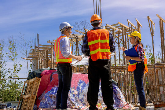 Structural engineer, architect and foreman worker with blueprints discuss, plan working for the outdoors building construction site. Construction collaboration concept