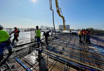 Naklejka premium Construction workers pouring concrete slab at a commercial job site