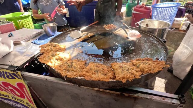Thai Street Food Vendor Frying Oyster Omelets on Large Flat Griddle