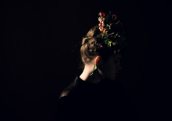 Elegant woman's profile portrait showing intricate braided updo with a beautiful flower and leaf crown © Evgenii Bakhchev