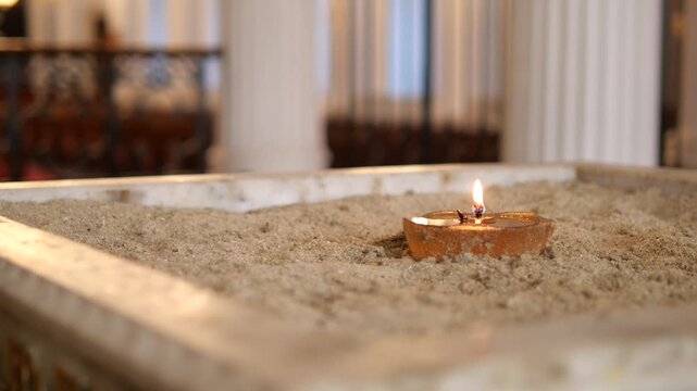 Candle burning on a sand altar in a church