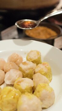 Pouring Soy Sauce Over Steamed Shumai and Har Gow Dim Sum Dumplings