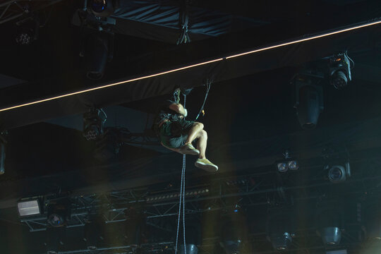 Rigger hanging on rope installing stage lighting with copy space