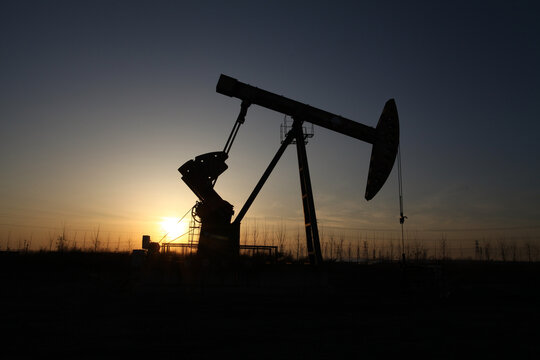Silhouette of Oil Pump Jack at Oilfield During Sunset
