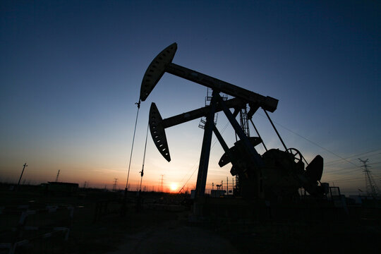 Oil Pump Jack Silhouette at Sunset with High-voltage Towers