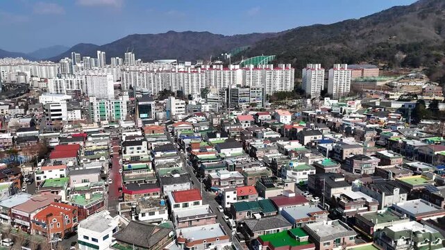 Drone aerial footage of residential urban district dense buildings private houses and apartment blocks with mountains urbanization overpopulation city growth South Korea