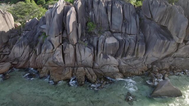 cinematic aerial drone shot reveals the dramatic, rugged coastline, massive, ancient granite boulders sculpted of Anse Grosse Roche on La Digue Island, Seychelles 007 30fps