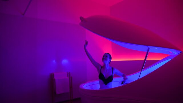 Pink lit room as woman finishes floatation therapy session in deprivation pod