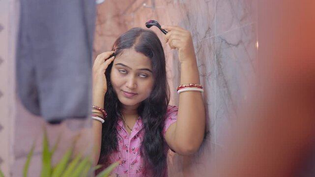 Indian housewife using derma roller on scalp in front of a bathroom mirror, microneedling treatment for hairloss.