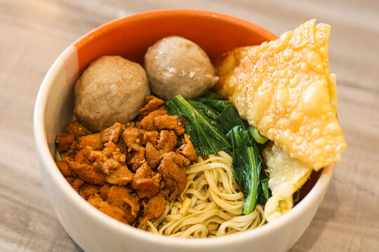 Chicken noodles served with meatballs and a crispy fried wonton in a bowl.