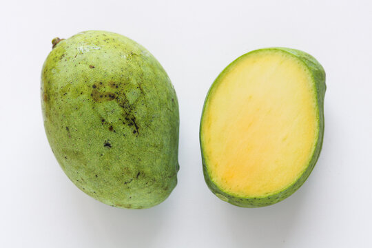 Indramayu mangoes shown whole and cut open, highlighting smooth skin and yellow flesh.
