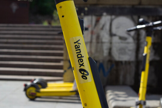 Tbilisi, Georgia - April 23, 2026: Horizontal street city photo. Yellow electric scooter with Yandex Go logo close up on parking lot. Concept of kick scooter sharing, road trip, job, eco, power, rent