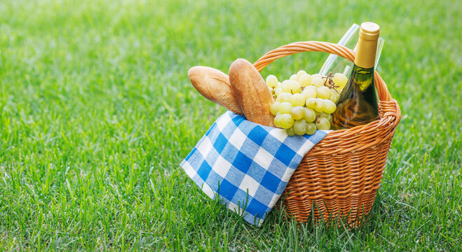 Picnic basket with wine, grapes, and baguette