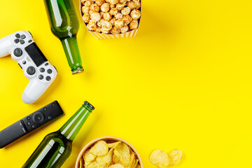 Popcorn, potato chips, beer and gamepad on yellow background © Evgeny Karandaev
