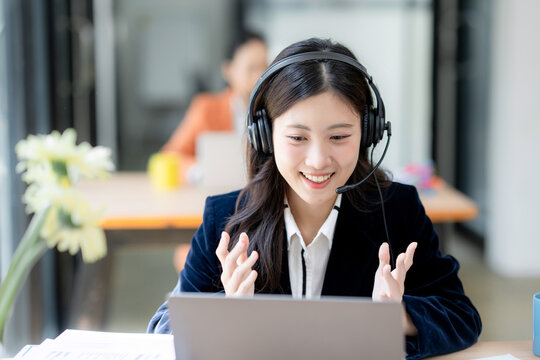 Smiling businesswoman in headset discussing with customer during online video conference call at modern office workplace