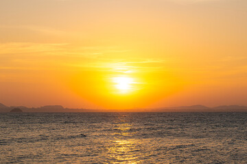 Obraz premium nature sky breathtaking golden sunset over a calm ocean, with the entire sky and water bathed in brilliant shades of yellow and orange. Streaky clouds enhance the dramatic display 