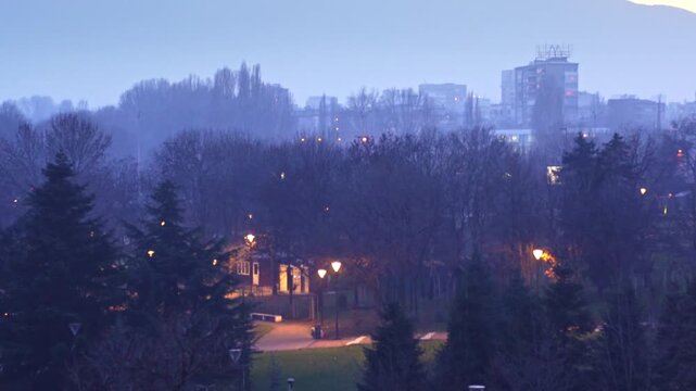4K winter shot at dusk (evening) with beautiful pink and blue sky with trees, lights and the Vitosha mountain in the background in the city center of Sofia, Bulgaria in Eastern Europe.