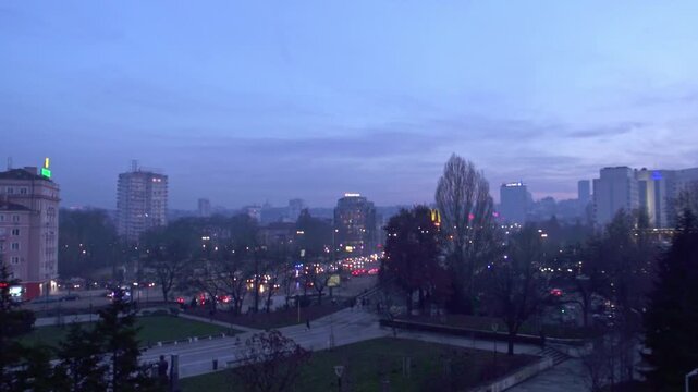 4K winter shot at dusk (evening) with beautiful pink and blue sky with trees, lights and the Vitosha mountain in the background in the city center of Sofia, Bulgaria in Eastern Europe.